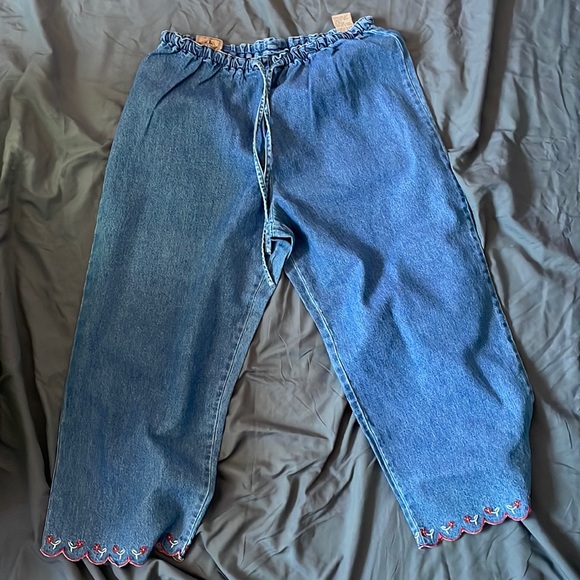 AMI jean pants with red and white designs on the front of the legs